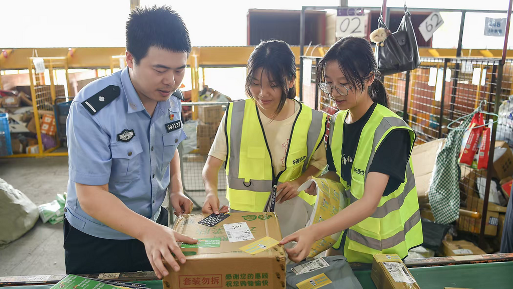 民警与快递工作人员一起给快递贴上反诈贴纸。 警方供图