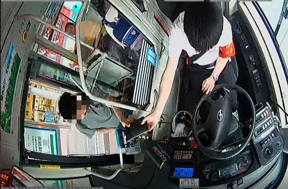 乘客把黑色手包带上车给公交驾驶员。视频截图